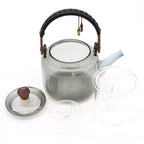 Clear glass teapot with wooden handle and accents on a white background