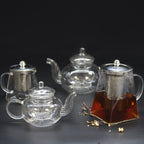 Set of glass teapots with metal lids on a dark background