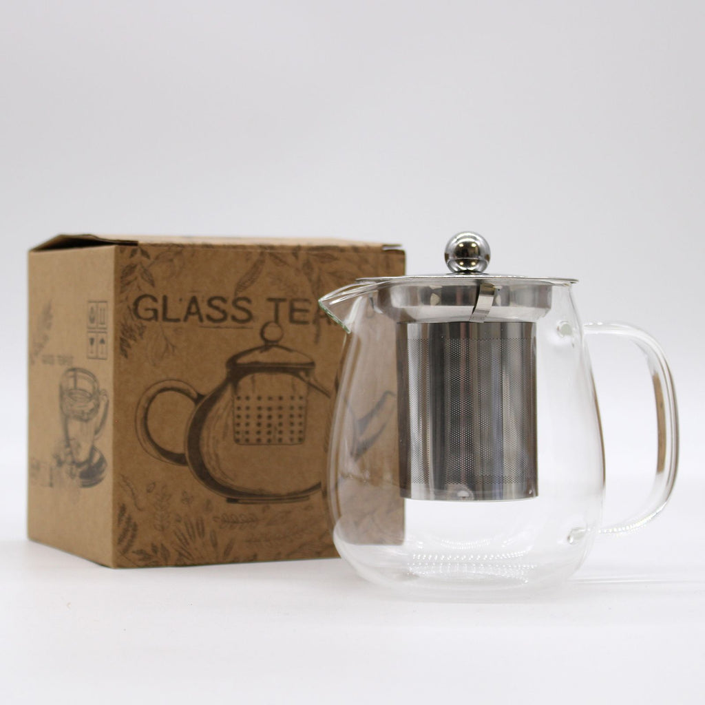 Clear glass teapot with metal lid and handle next to a cardboard box labeled 'Glass Teapot'.