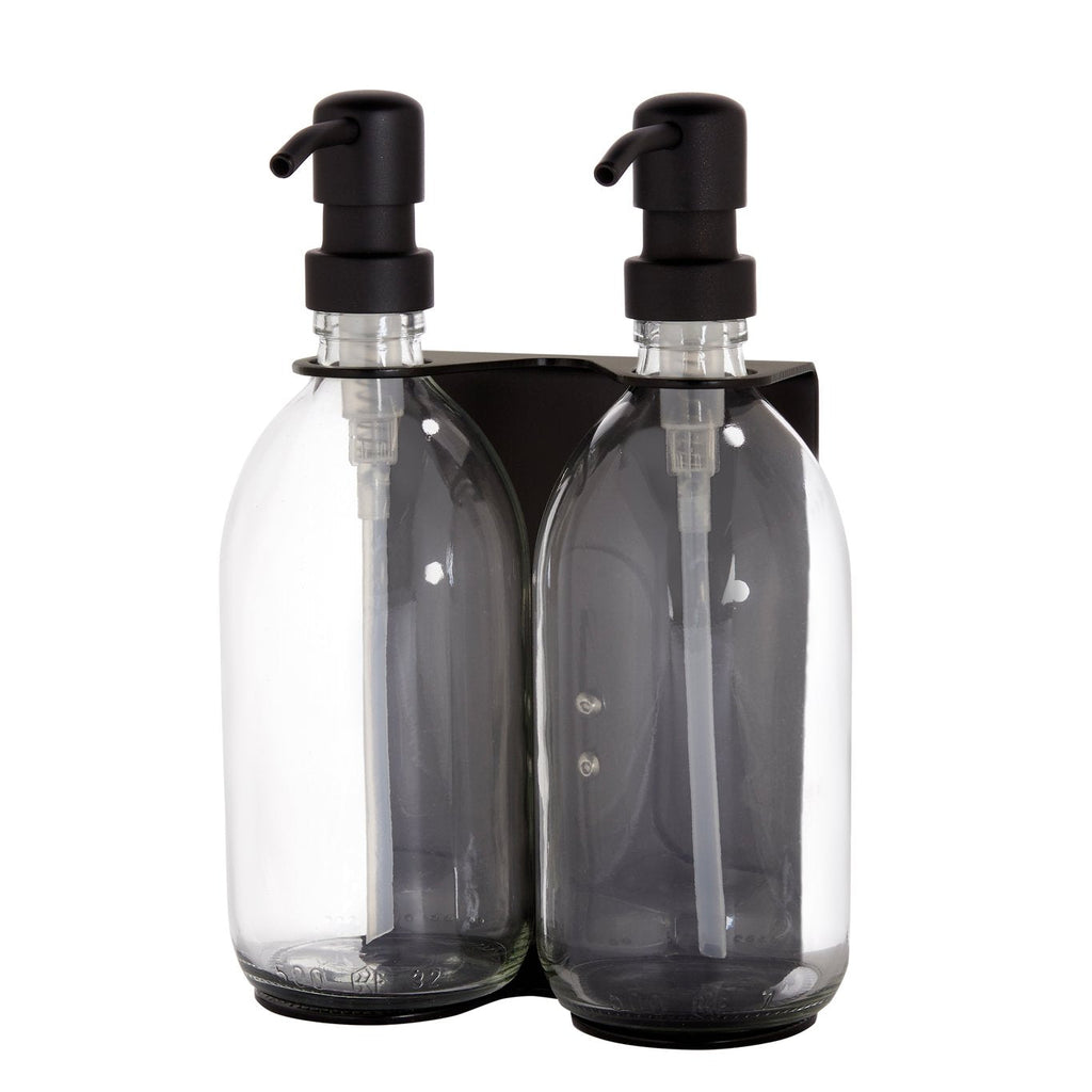 Two clear bottles with black pumps in a black holder on a white background