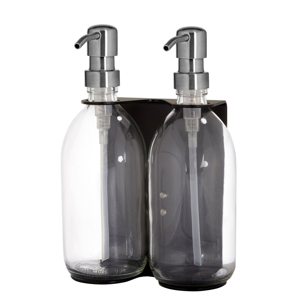 Two clear glass bottles with silver pumps in a black holder on a white background