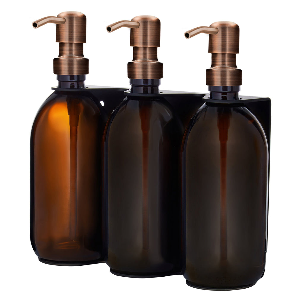 Three amber glass bottles with bronze pumps on a white background