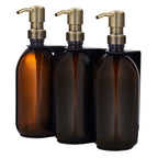 Three amber glass bottles with bronze pumps on a white background