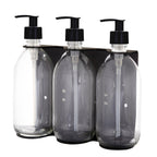 Three clear glass bottles with black pump dispensers on a white background
