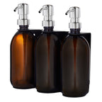 Three amber glass bottles with silver pump dispensers on a white background