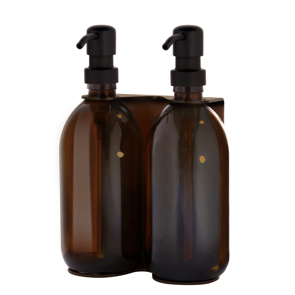 Two brown glass bottles with black pumps in a holder on a white background