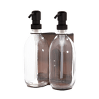 Two clear glass bottles with black pumps in a metal holder on a transparent background