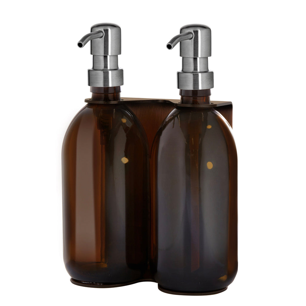 Two brown bottles with silver pumps in a holder on a white background