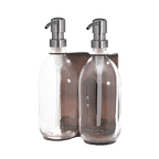 Two clear glass bottles with silver pumps on a dark teal background