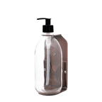 Clear soap dispenser with black pump on a dark green background