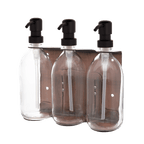 Three clear glass bottles with black pumps in a metal holder on a dark background