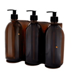 Four amber glass bottles with black pumps in a clear packaging holder on a white background