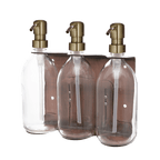 Three clear bottles with gold pumps in a metallic holder on a gradient background