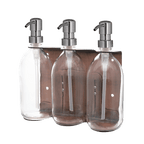 Three clear glass bottles with silver pumps in a metal holder on a dark green background