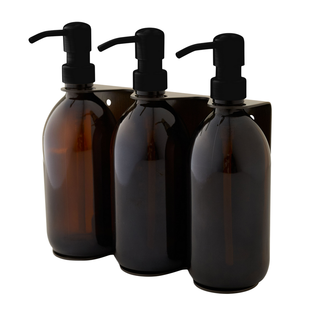 Three amber glass bottles with black pumps on a white background