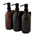 Three amber glass bottles with black pumps on a white background