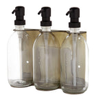 Three clear glass bottles with black pump dispensers on a white background