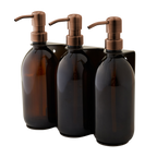 Three brown glass bottles with bronze pumps in a black holder on a white background