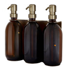 Three brown glass bottles with brass pumps on a white background