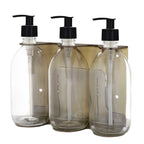 Three clear glass bottles with black pump dispensers on a white background