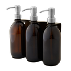 Three amber glass bottles with silver pumps in a black holder on a white background