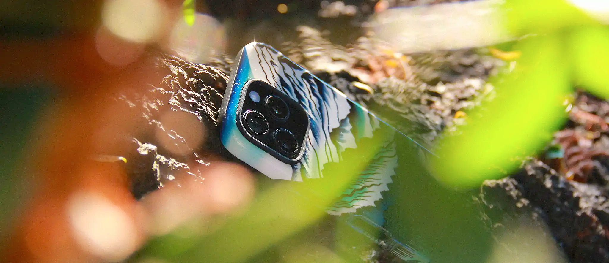 iPhone 15 Pro with a unique case design from MVB STUDIO, surrounded by green leaves and natural elements.