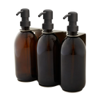 Three amber glass bottles with black pumps in a holder on a white background