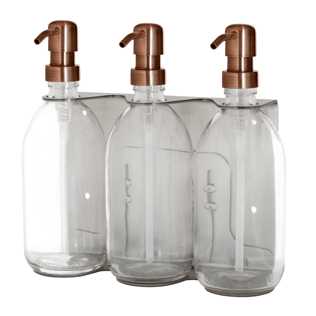 Three clear glass bottles with copper pumps on a transparent background