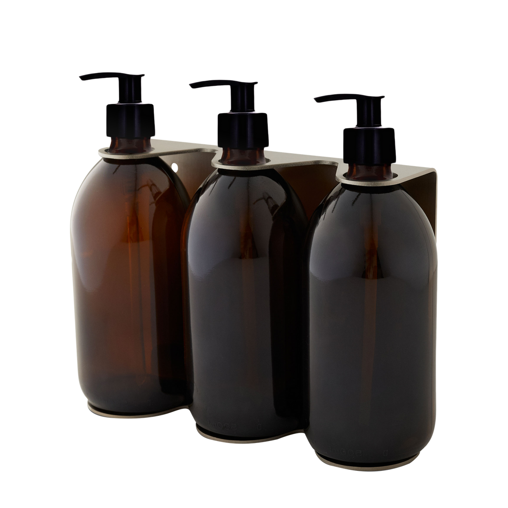 Three amber glass bottles with black pump dispensers on a white background