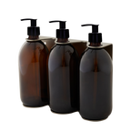 Three amber glass bottles with black pump dispensers on a white background