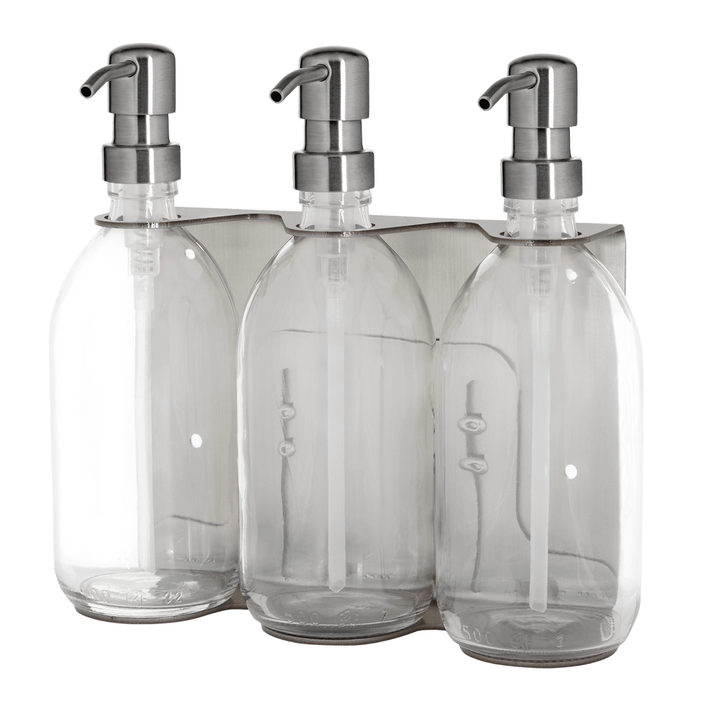 Three clear glass bottles with silver pumps in a packaging tray on a dark background