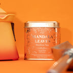 Mandala Leaves Rooibos Tea canister on an orange background with a teapot and cup.
