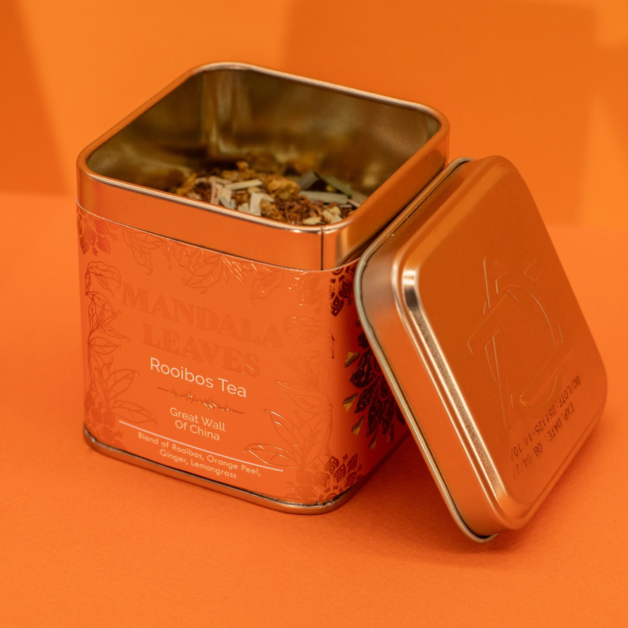 Open orange tea tin with 'Rooibos Tea' label on an orange background