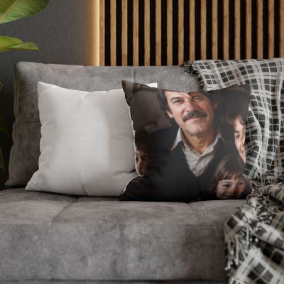 A square throw pillow featuring a printed portrait of a man with a mustache, styled on a gray sofa alongside a plain white pillow and a black-and-white plaid throw blanket.