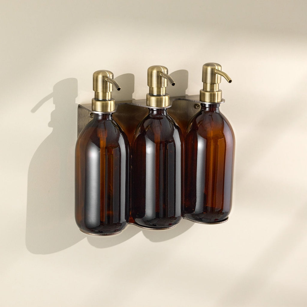 Three brown glass bottles with gold pumps on a beige background