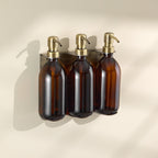 Three brown glass bottles with gold pumps on a beige background