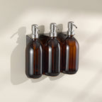 Three brown glass bottles with silver pump dispensers on a beige background
