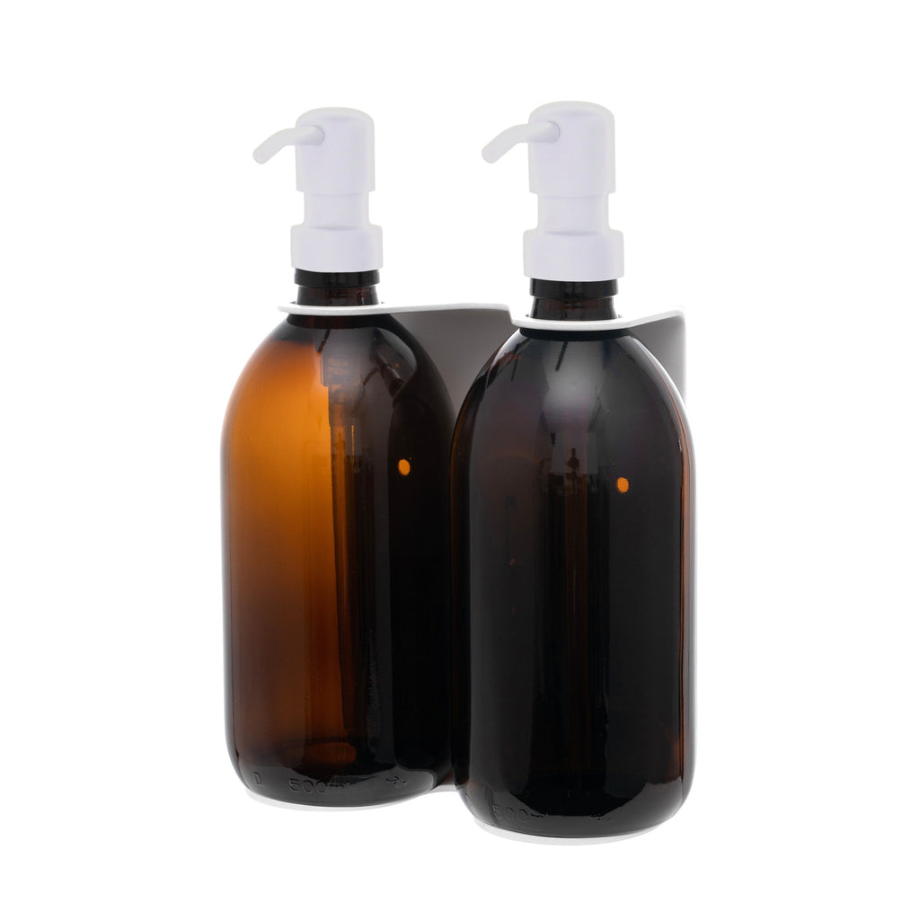 Two amber glass bottles with white pump dispensers on a white background